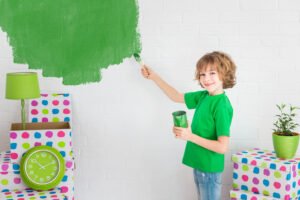 niño pintando la pared verde